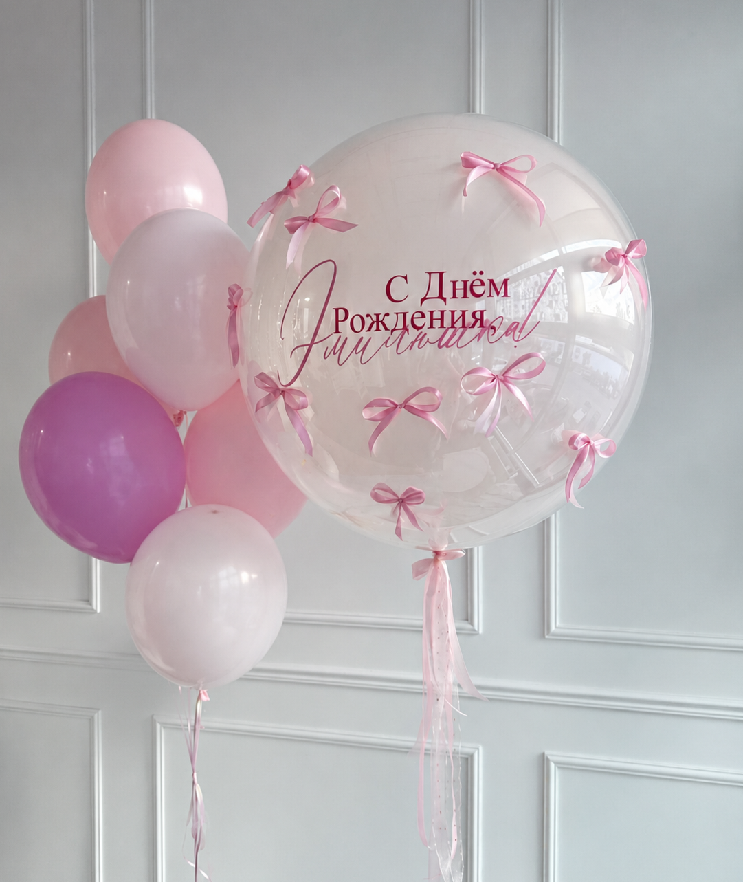 Композиция для девочки с большим прозрачным Bubble с поздравительной надписью и розовыми бантиками, розовыми, сиреневыми и белыми воздушными шарами