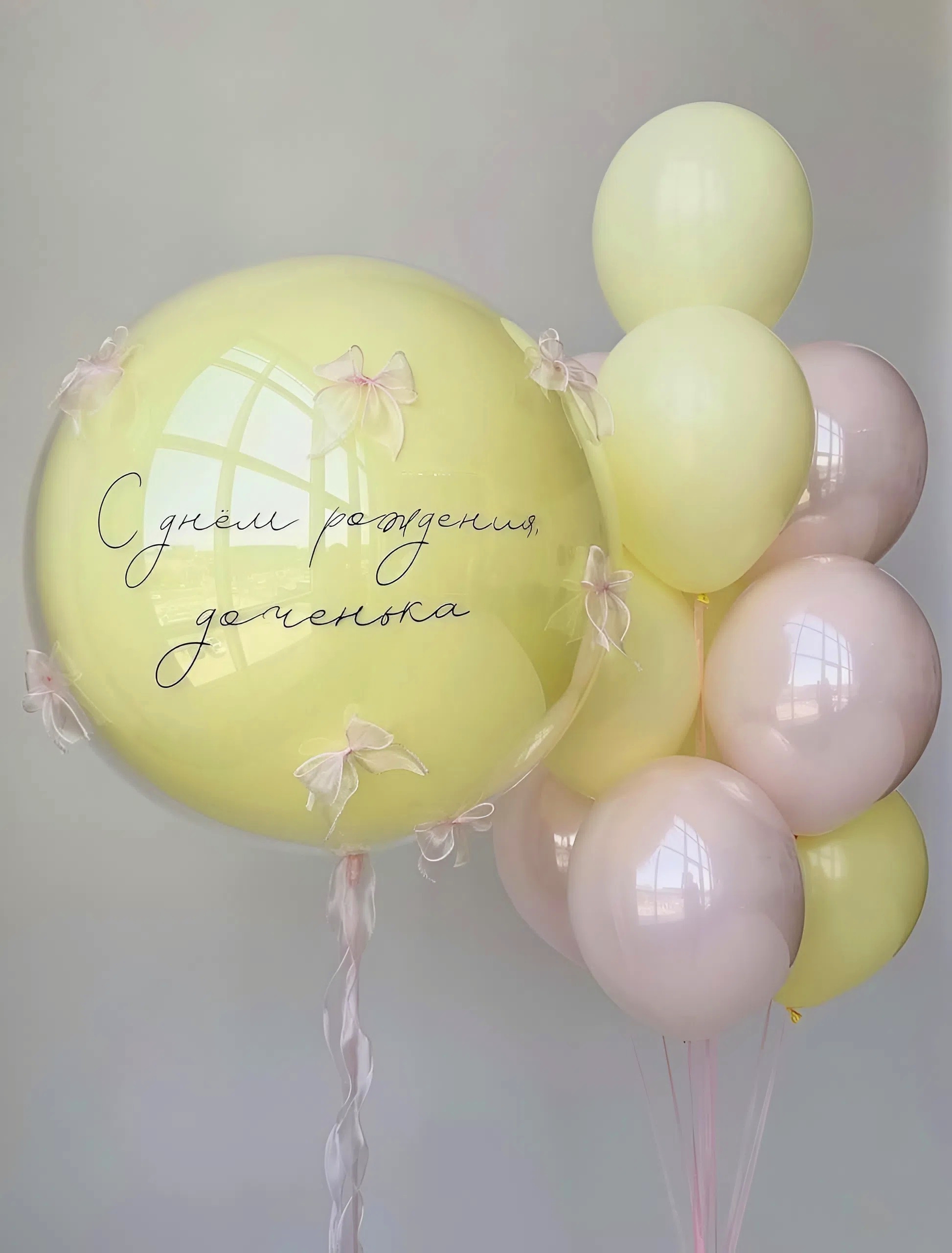 Композиция для девочки с большим Bubble с надписью С днем рождения доченька, бантиками и розово-желтыми воздушными шарами